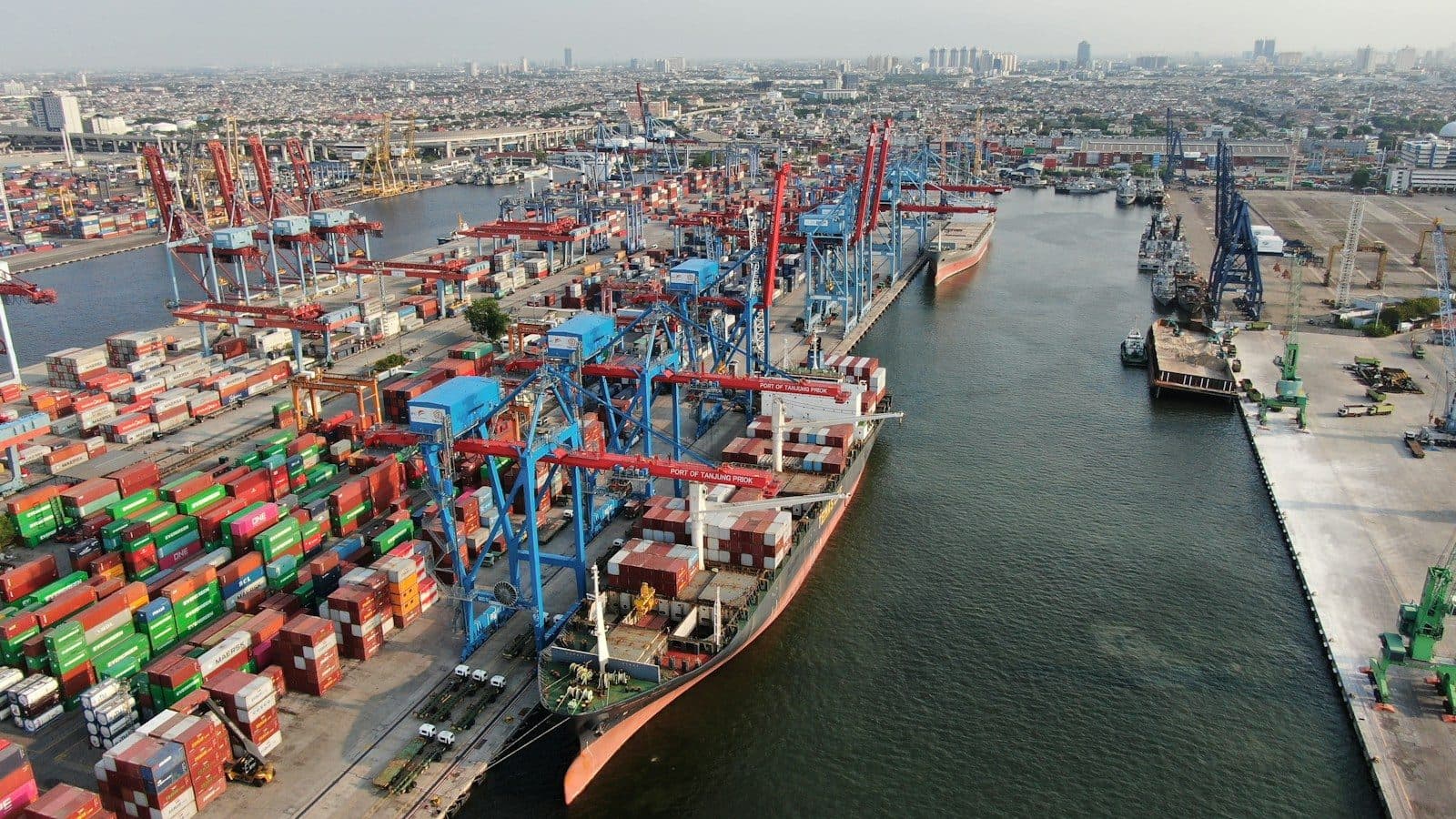 Vue aérienne d'un port à conteneurs, avec ses grues et ses navires à quai.